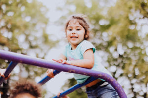 little girl on monkey bars outside